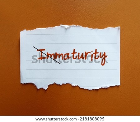 Torn paper on orange background with handwritten text cross off IMMATURITY to MATURITY, means to improve from being person who thinks and acts like child to be immature, think and act like adult
