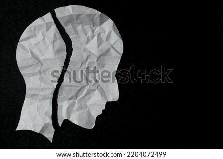 Torn paper in the shape of a person's head on a black background. mental health issues, Anxiety, depression, broken mood and mindfulness awareness concept.
