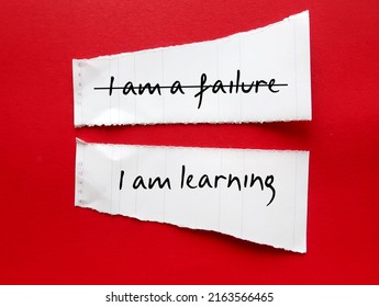 Torn paper stick on red background with handwriting I AM A FAILURE, corrected to I AM LEARNING, to overcome negative self talk, replace with positive thoughts, with respect and self worth - Shutterstock ID 2163566465