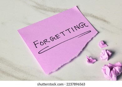 Torn paper with the text Forgetting with crumbled paper balls. Dementia and disremembering concept.  