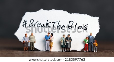 Torn paper with the word ‘BreakTheBias' written on it. Break the bias campaign with miniature several people.