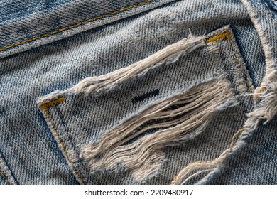 Torn Pocket On Old Blue Jeans. Blue Retro Jeans Fabric Background Or Denim Texture. Close Up View