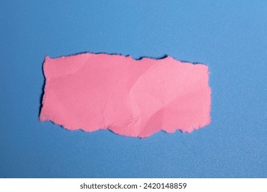Torn rectangular pink construction paper on a blue background.