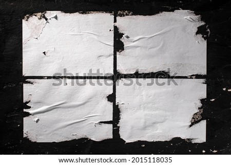 Torn sheets of white paper glued to the black wall.