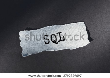A torn snippet of paper with the acronym SQL written on it rests on a dark background.