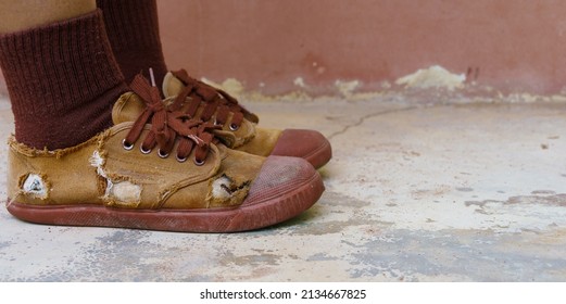 Torn student shoes, Poverty of rural schoolchildren often cannot afford new shoes, high school student legs wearing torn shoes, poor shortage of educational equipment, worn-out brown old sneakers