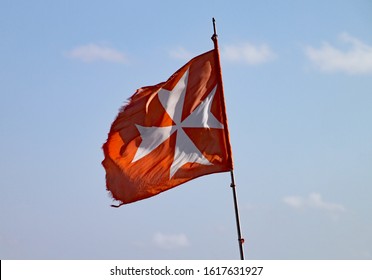 A Torn And Tattered Maltese Cross Flag Flies On A Fishing Boat In Marsaxlokk In Malta