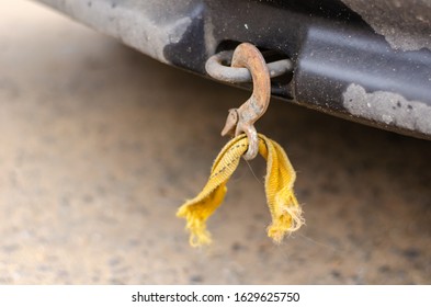 Torn tow rope on towing loop. Rusty hook with the rest of the orange cable. Violation of towing rules. Close-up. Selective focus. Without people. Landscape photo arrangement.