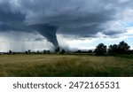 Tornado forming over farmland, dramatic storm clouds touching ground