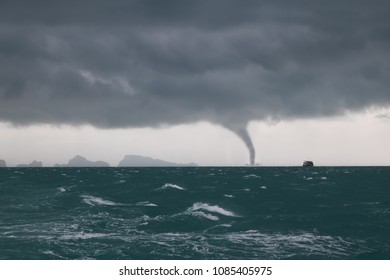Tornado and storm cloud in the sea while the ship is sailing.