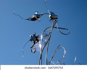 Toronto, Canada -08.17.2012: Edwards Gardens, Entry Garden. Stainless Steel Modern Garden Sculpture By Ron Baird. Titled The Garden Web. Abstract, Low Angle View. Flowers With Long Stem And Spider Web