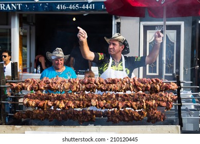 TORONTO, CANADA - 10 AUGUST 2014: A man dancing behind a food stall during the Taste of Danforth Street Festival