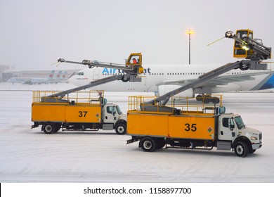 TORONTO, CANADA -14 APR 2018- View of de-icing trucks removing frost and ice near airplanes during a winter snow storm at the Toronto Pearson International Airport (YYZ) in Canada.