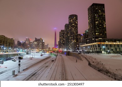 TORONTO, CANADA - 3RD FEBRUARY 2015: A View Of Downtown Toronto In The Winter Showing Snow On The Railway Tracks And The CN Tower In The Clouds.