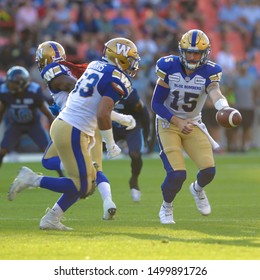 Toronto, Canada - Aug 1, 2019: Winnipeg Blue Bombers Quarterback Matt Nichols (15) Handing The Ball Off During Winnipeg Blue Bombers At Toronto Argonauts Game At BMO Field In Toronto, ON