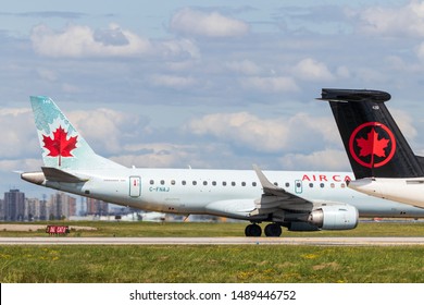 TORONTO, CANADA - August 23, 2019: Two Air Canada tails (old livery and new livery) holding short beside runway at Toronto Pearson Intl. Airport. 