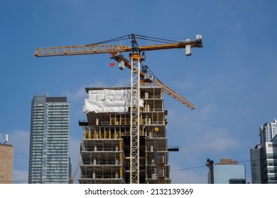 Toronto Canada Feb 13 2022: Tall Construction Crane In The City Downtown Building A New Highrise Development Against Clear Blue Sky. Real Estate New Starts, Housing Market Concept.