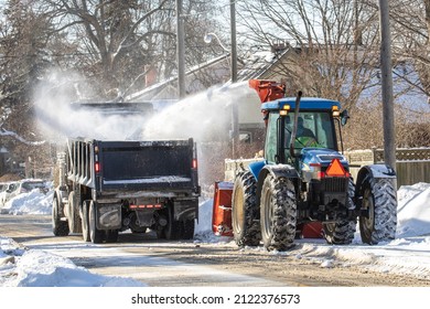 Toronto, Canada, February 5, 2022; A Large Farm Tractor Driven Snow Snow Blower And Dump Truck Clearing Snow From The Roadway After A Large Snowfall