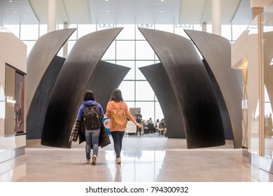 TORONTO, CANADA - JANUARY 2, 2018: PEOPLE WALK BY "TILTED SPHERES" BY RICHARD SERRA IN TERMINAL 1 AT PEARSON INTERNATIONAL AIRPORT. 