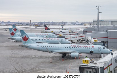 TORONTO, CANADA - JANUARY 8, 2018: New Air Canada Embraer 190 regional passenger jets arrive at the terminal building of Toronto Pearson International Airport at dawn. The Toronto skyline is visible.
