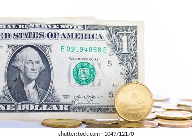 Toronto, Canada - March 19, 2018: Canadian One Dollar Coin Over Shadowed By An American Dollar Bill