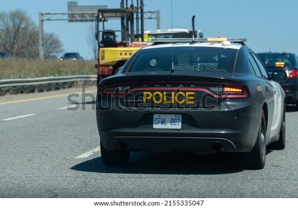 Toronto Canada May 7 2022: Close view of OPP\
Dodge Charger police cruiser interceptor following a car on the\
highway. Dangerous, careless driving, speeding, DUI, traffic\
violations concept.