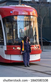 Toronto, Canada - Nov 14, 2020: Urban Scene - Female Streetcar Driver Standing In Front Of The Tram  Having A Smoke During Her Brake. Selective Focus.