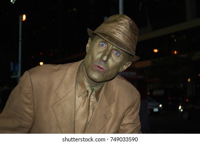 TORONTO, CANADA - October 27, 2017 - Gold Mime, Street Artist, Living Statue, Man Posing In Frozen Position And Will Only Move When Money Donation Is Given. Artist At Dundas Square, Downtown, At Night