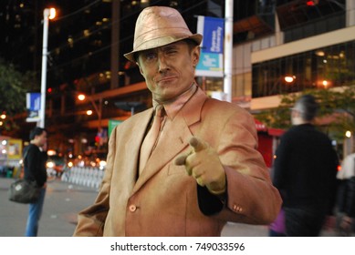 TORONTO, CANADA - October 27, 2017 - Gold Mime, Street Artist, Living Statue, Man Posing In Frozen Position And Will Only Move When Money Donation Is Given. Artist At Dundas Square, Downtown, At Night