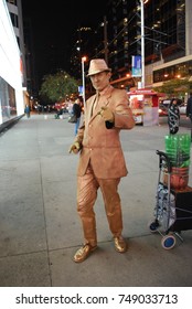 TORONTO, CANADA - October 27, 2017 - Gold Mime, Street Artist, Living Statue, Man Posing In Frozen Position And Will Only Move When Money Donation Is Given. Artist At Dundas Square, Downtown, At Night