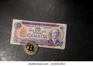 Toronto, Canada - October 30. 2021: Ten Canadian Dollar Banknote With Gold Bitcoin Coin. Cryptocurrency And CAD Dollar Bill. Trade Digital Assets In Canada Concept.