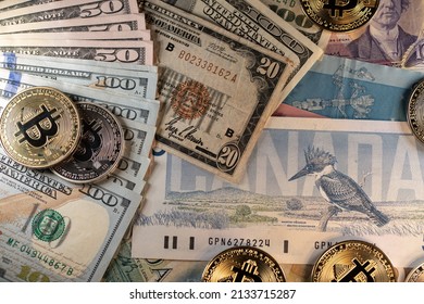 Toronto, Canada - October 30. 2021: Bitcoin on Canadian and US Dollar banknotes, modern and old monetary systems. Historic 20 USD bill next to BTC and beautiful Birds of Canada banknote