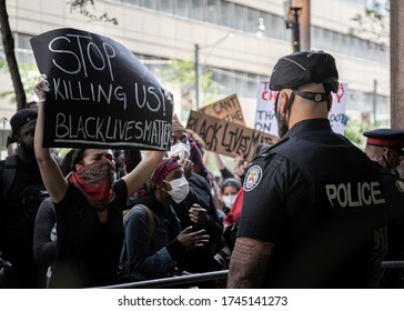 Toronto, Canda, May 30, 2020: 'Not another black life' protest. Protest against police brutality. Black lives matter Toronto. Protester confronting a police officer. 'Stop killing us' sign