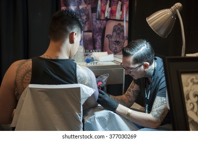 TORONTO - JUNE 19 :  A tattoo artist working closely on a tattoo on his clients arm during the Toronto Tattoo convention on June 19, 2015 in Toronto, Canada.