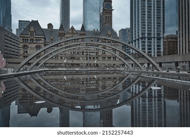 Toronto Ontario, Canada- April 26th, 2022: Toronto’s Old City Hall Reflection Into The Pool At Toronto City Hall’s Nathan Phillips Square.