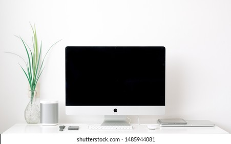 Toronto, Ontario / Canada - August 23rd 2019 : Photograph of an iMac with an apple mouse and Apple Watch and iPhone and apple keyboard with a white wall.