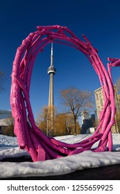 Toronto, Ontario, Canada - February 14, 2018: Purple Stick Art Circle At HTP Park In Toronto With Snow In Winter And CN Tower Against A Blue Sky