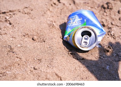 Toronto, Ontario, Canada - July 6, 2021: Shadow Of Hand Picking Up Empty Aluminum Nestea Can On Sandy Beach. Environmental Protection And Recycling Concept.