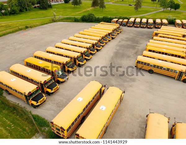 Toronto, Ontario, Canada. June 10, 2018. The\
parking full of school buses waiting for educational season. Row\
filled with many school bus ready to pick up students to school.\
Drone aerial view.