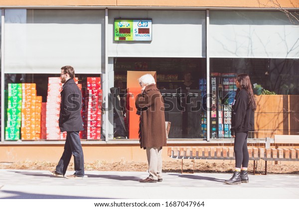 TORONTO, ONTARIO, CANADA - MARCH 28, 2020: PEOPLE\
PRACTICE \'SOCIAL DISTANCING\' WHILE WAITING IN LINE TO ENTER GROCERY\
STORE. SOCIAL DISTANCING IS BEING ENFORCED DUE TO COVID-19\
WORLDWIDE PANDEMIC. 