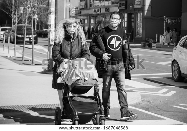 TORONTO,\
ONTARIO, CANADA - MARCH 28, 2020: PARENTS WEARING FACE MASK DUE TO\
COVID-19 WORLDWIDE PANDEMIC WALK WITH STROLLER.\
