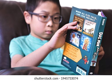 Toronto, Ontario, Canada - March 29, 2021:Selective focus of boy reading latest graphic novel comics dog man book Mothering Heights during covid-19 pandemic lockdown. Child self learning.
