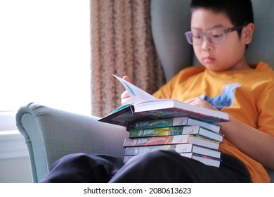 Toronto, Ontario, Canada - November 21, 2021: Student Boy Reading Library Borrowed Set Series Of Graphic Novel Comics Books -Klawde: Evil Alien Warlord Cat At Home.
