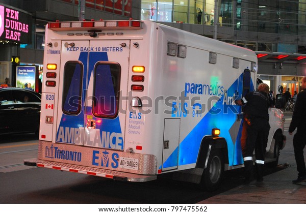 TORONTO, ONTARIO, CANADA - October 27 2017 -\
Ambulance At Dundas Square on Yonge Street, city, 911, Emergency,\
crash, Accident on the road, injuries, paramedics with stretcher,\
flashing lights, aid