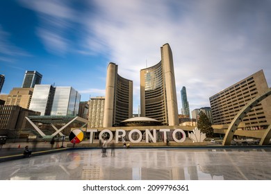 TORONTO, ONTARIO - DEC 2021: TORONTO Sign At Nathan Phillips Civic Square People Skating At The Public Skating Rink In Front Of City Hall  .Winter Holiday Events