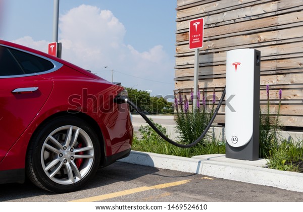 TORONTO, ONTARIO - July 26, 2019: Tesla Urban\
Supercharger at CF Sherway Gardens Mall with Tesla Model S\
plugged-in and charging.\
