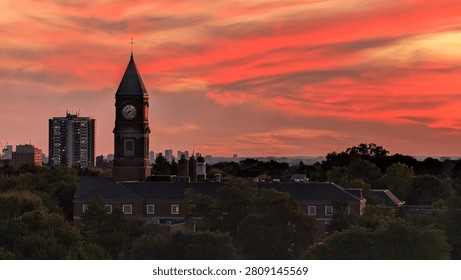Toronto skyline at sunset with dramatic red clouds and historic clock tower silhouette in Ontario, Canada. Urban evening cityscape and travel destination concept.