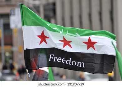 TORONTO-MARCH 16: A protester waiving a Syrian flag during a protest rally organized to raise awareness and commemorate two years of Syrian revolution on March 16, 2013 in Toronto, Canada.