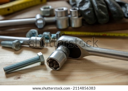 Torque wrench, work tool with reversible ratchets on wooden background. Hand tool for screw and nut tighten. Workshop table, closeup view