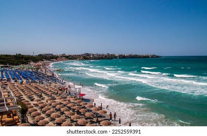 Torre dell'Orso beach in Lecce, Italy. Beach between cliffs crowded with umbrellas and bathers looking to cool off in its warm turquoise waters during the summer. - Shutterstock ID 2252559391